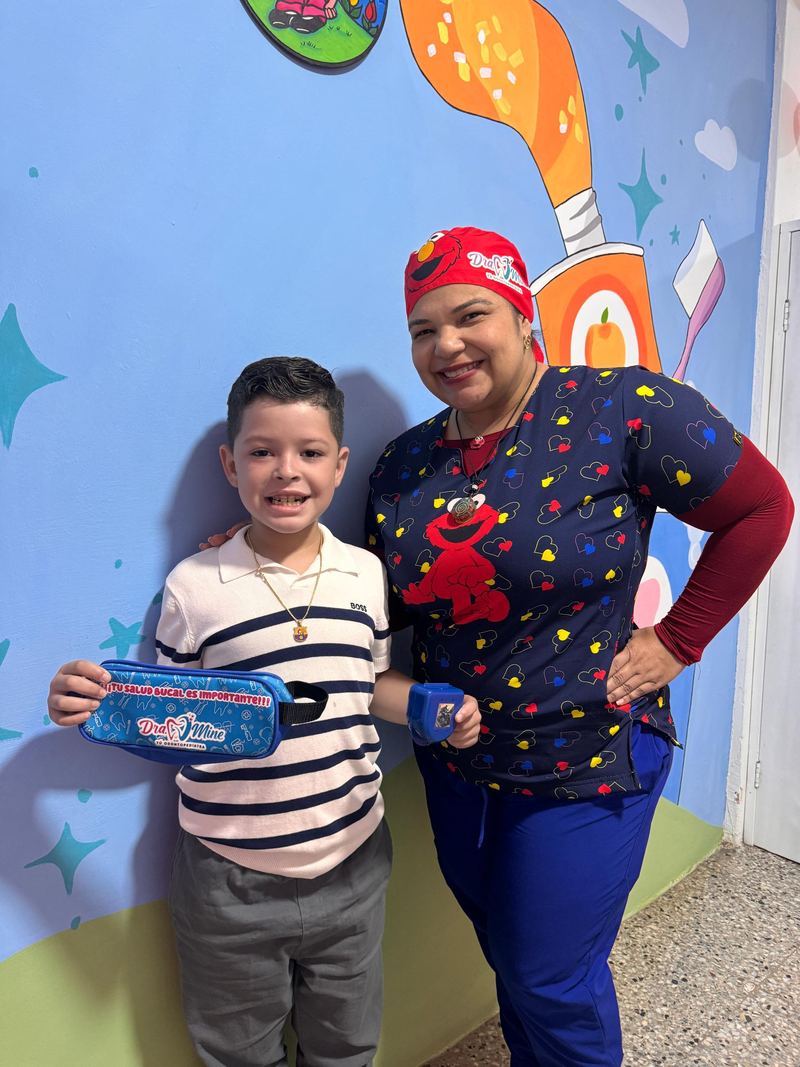 La Dra. Mine junto a un niño que muestra su estuche de salud bucal Dra. Mine